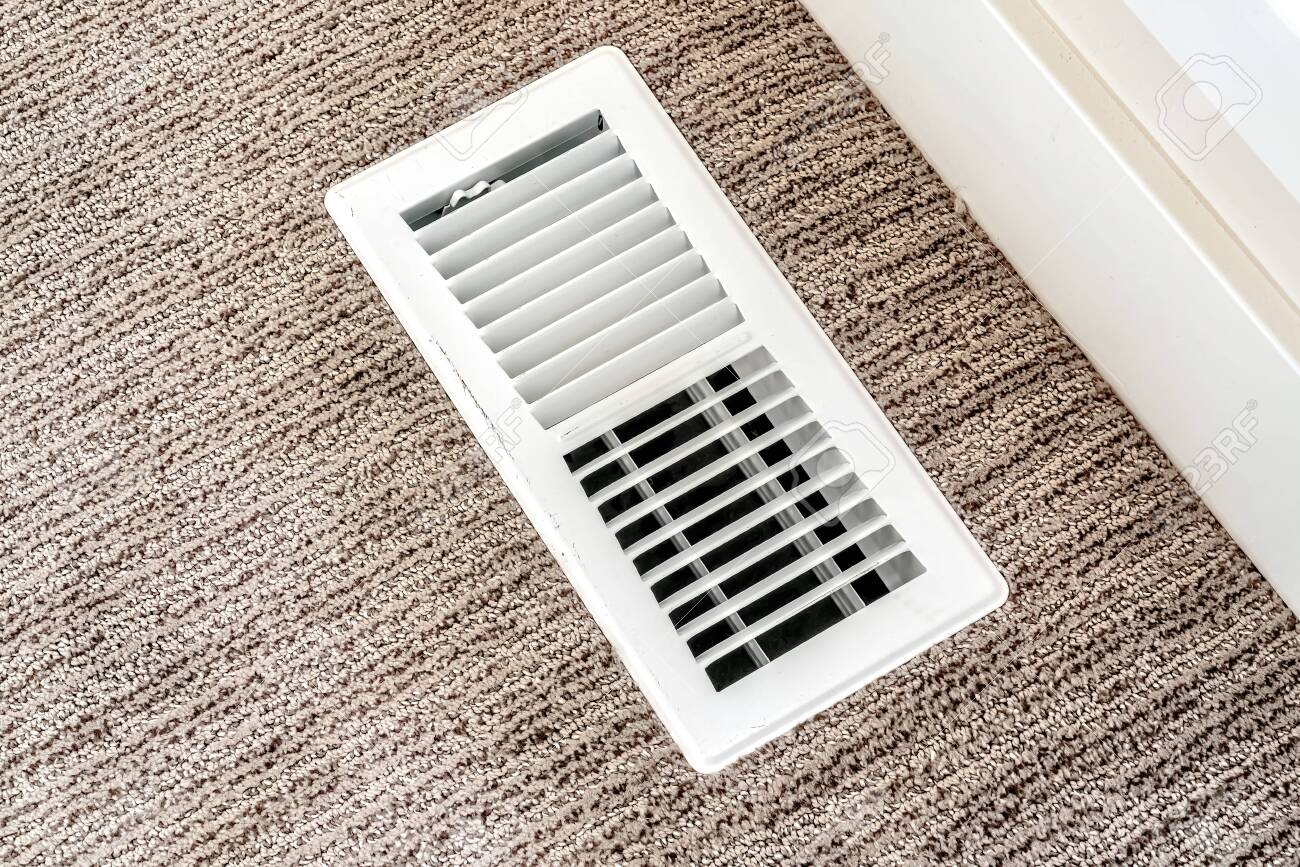 White air conditioner duct grille cover against floor with brown carpet