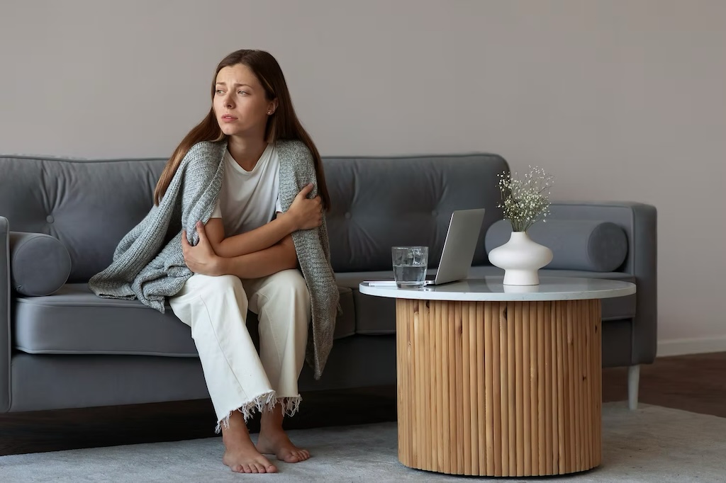 woman sitting on couch looking cold
